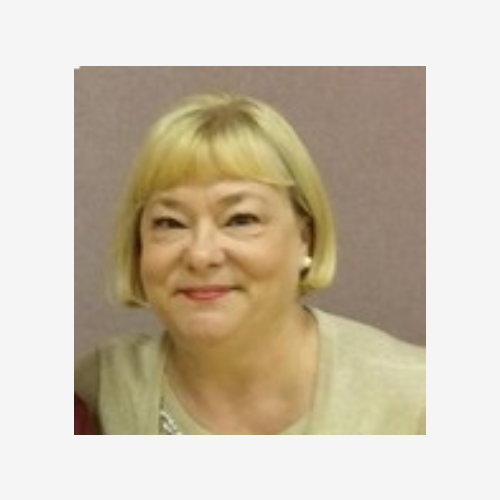 A woman with blonde hair and a beige shirt.