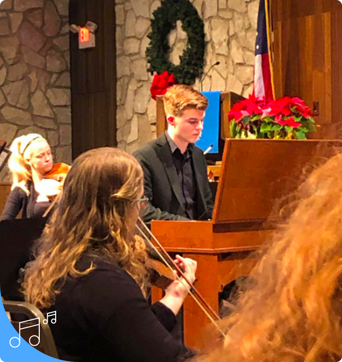 A man playing the violin in front of other people.