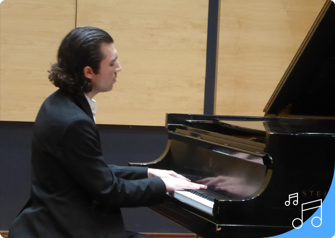 A man playing the piano in front of a wooden wall.