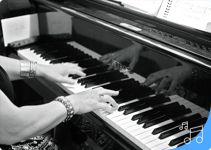 Two people playing a piano in black and white.