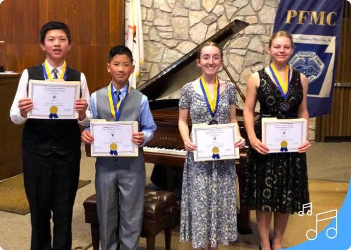 A group of young people holding certificates in front of a piano.