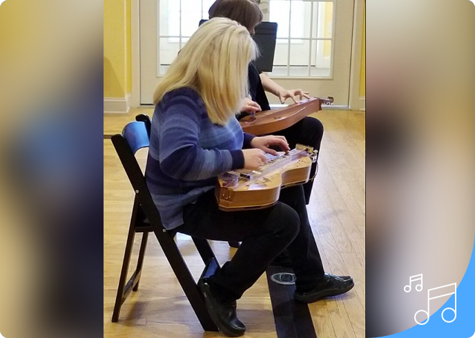 Two women sitting in chairs playing a guitar.