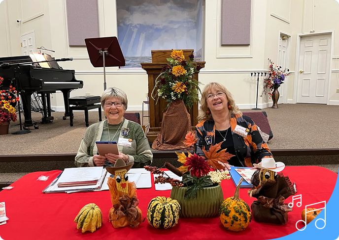 Two women sitting at a table with decorations on it.